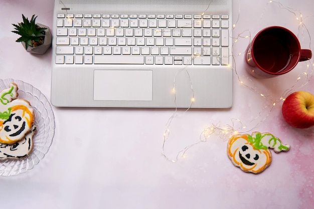 Cozy home office in Halloween laptop and red cup homemade cookies in shape of cute pumpkins