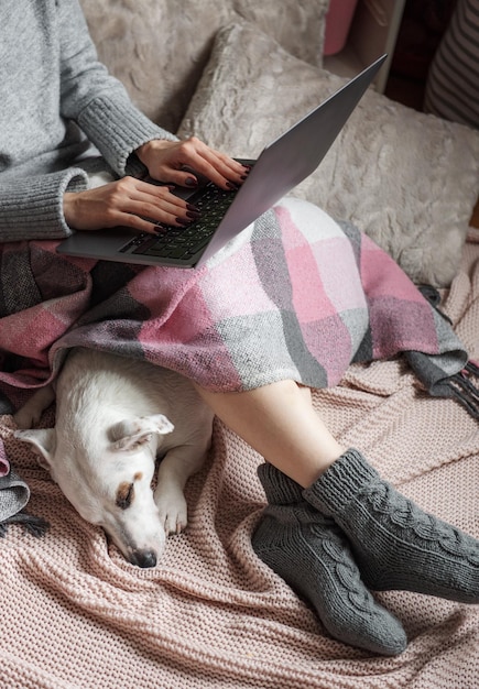 Cozy home woman covered with warm blanket drinks coffee sleeping dog next to woman