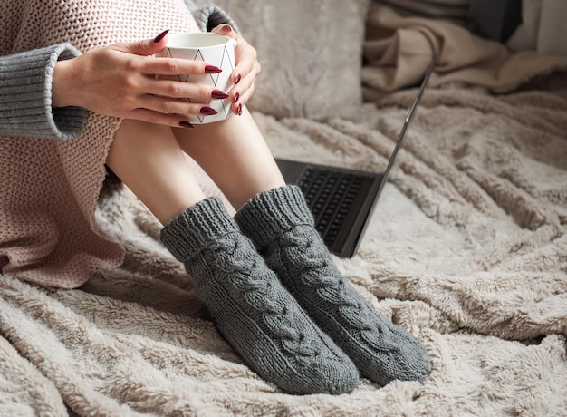 Cozy home woman covered with warm blanket drinks coffee