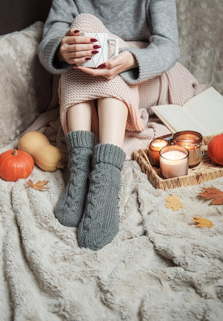 Cozy home woman covered with warm blanket drinks coffee