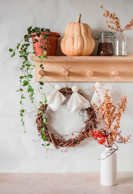 Cozy interior of the hallway Wooden hanger with flower pumpkin grape wreath and homemade paper ghost garland