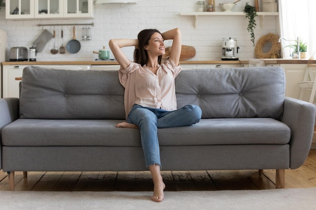 In cozy living room happy woman sitting on couch alone