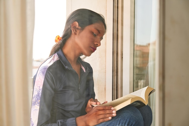 Cozy morning read by the window with a lovely Indian woman