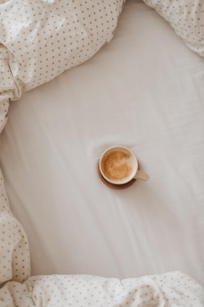 Cozy unmade bed with a coffee cup in the morning breakfast in bed