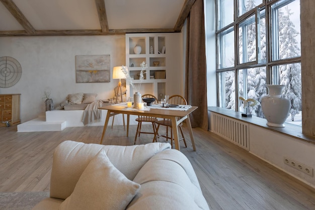 Cozy warm home interior of a chic country chalet with a huge panoramic window overlooking the winter forest open plan wood decoration warm colors and a family hearth