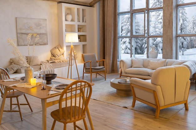 Cozy warm home interior of a chic country chalet with a huge panoramic window overlooking the winter forest open plan wood decoration warm colors and a family hearth