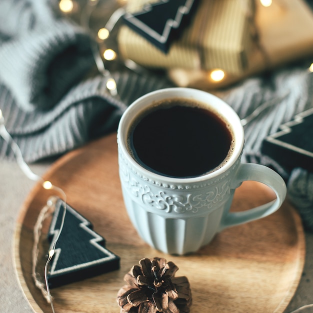 Cozy winter composition cup of coffee, present box, gifts, sweater. 