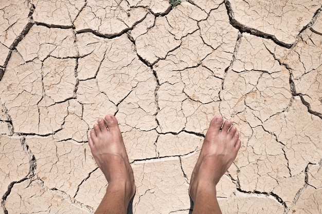 Crack dry ground on foot, drought concept.