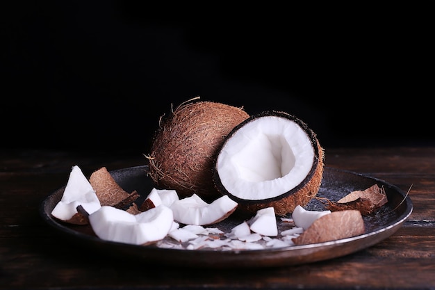 Cracked coconut on metal plate on rustic wooden table and dark background