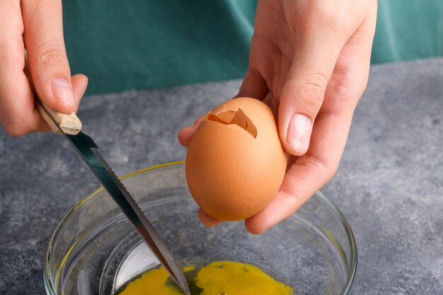 Photo a cracked egg in the hand close up a womans hand cracking an egg with knife