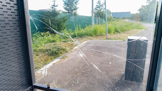 Cracked glass of bus stop and trash bin on village street premium photo