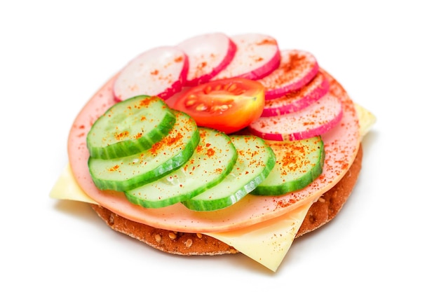 Cracker sandwich with fresh cucumber cheese sausage radish and tomato  isolated