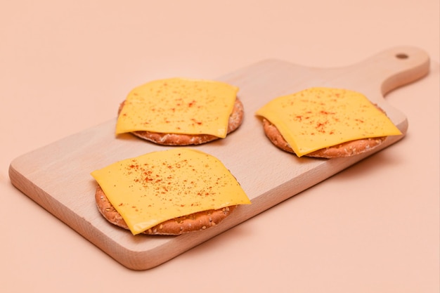 Cracker sandwiches with cheese and paprika on cutting board