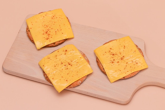 Cracker sandwiches with cheese and paprika on cutting board