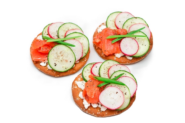 Cracker sandwiches with salmon cucumber radish cottage cheese and green onions  isolated