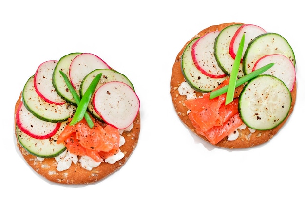 Cracker sandwiches with salmon cucumber radish cottage cheese and green onions  isolated