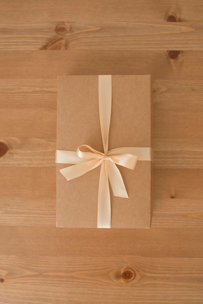 Craft box decorated with ribbon on a wooden table, natural packaging, gift.