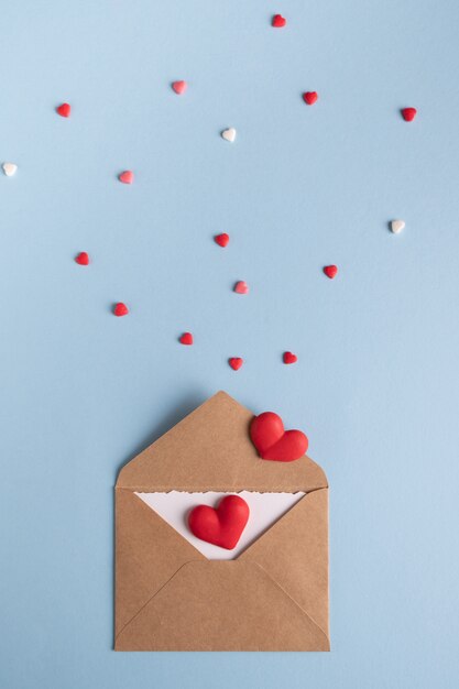 Craft envelope with white blank card and hearts on blue table.