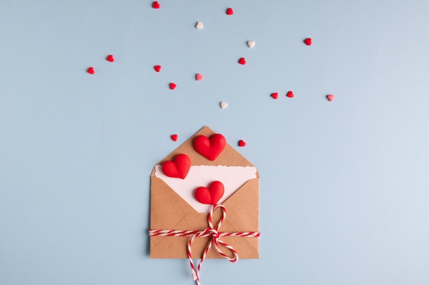 Craft envelope with white blank card and hearts on blue table