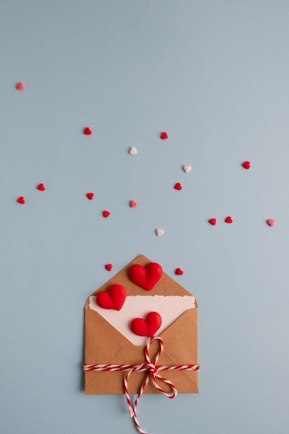 Craft envelope with white blank card and hearts on blue table