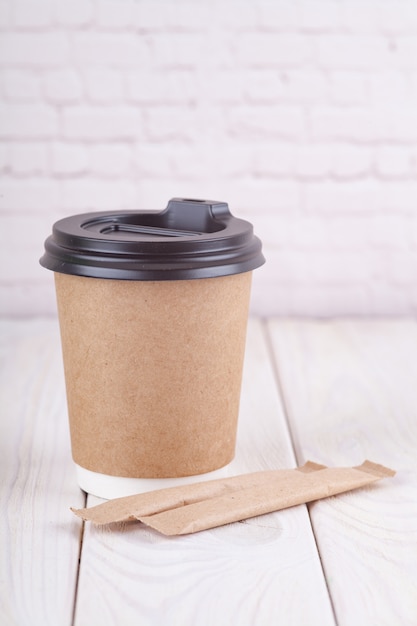 Craft paper coffee cups on a white table near light wall background