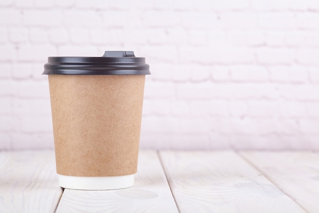 Craft paper coffee cups on a white table near light wall background