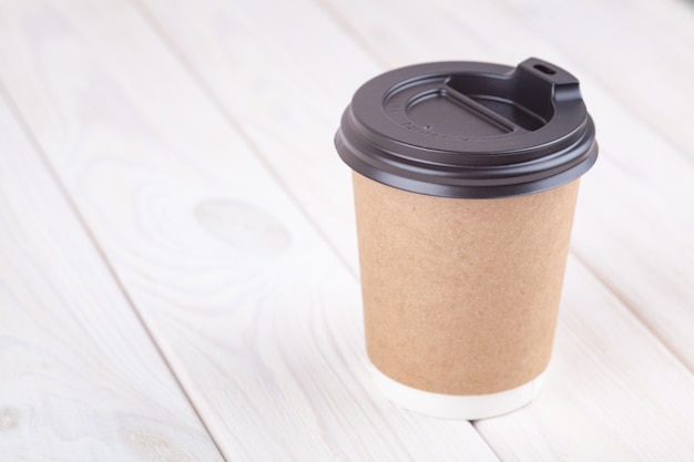 Craft paper coffee cups on a white table near light wall background