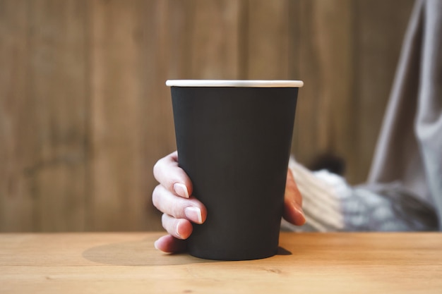 Craft paper cup of coffee  in a female hand in a coffee shop