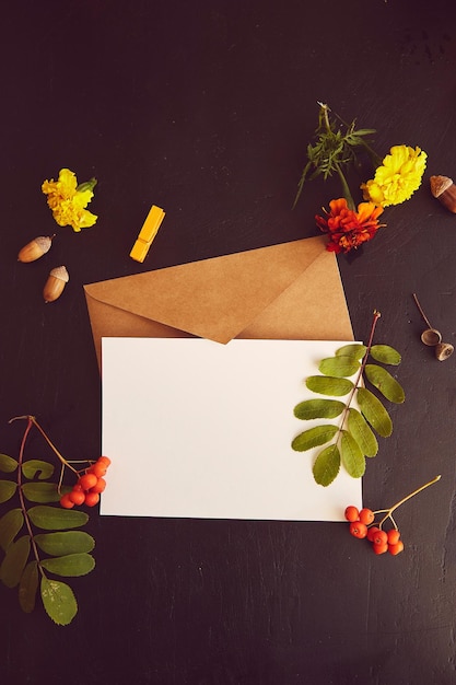 Crafting envelope with stationery card mockup among aesthetic autumn flowers and leaves Atmospheric background