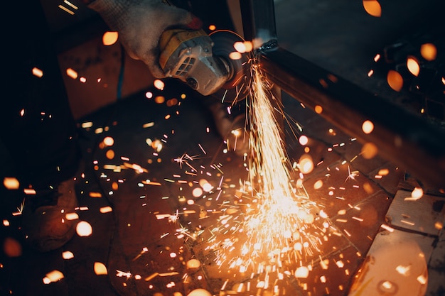 Craftsman sawing metal with disk grinder saw in workshop