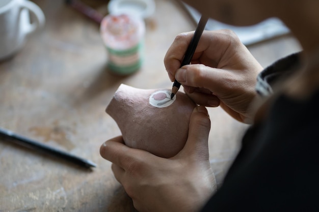 Craftsmaster makes interesting sketch drawing symbol on pitcher using pencil for doing draft