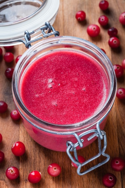 Cranberry curd in a glass jar on wooden table