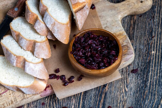 Cranberry and sliced soft fresh baguette on a cutting board and table