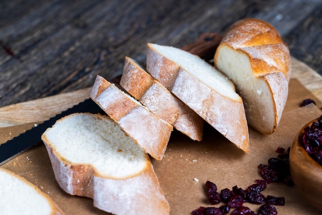 Cranberry and sliced soft fresh baguette on a cutting board and table