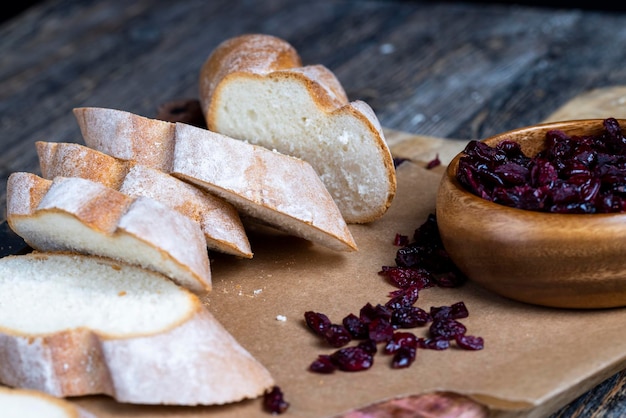 Cranberry and sliced soft fresh baguette on a cutting board and table