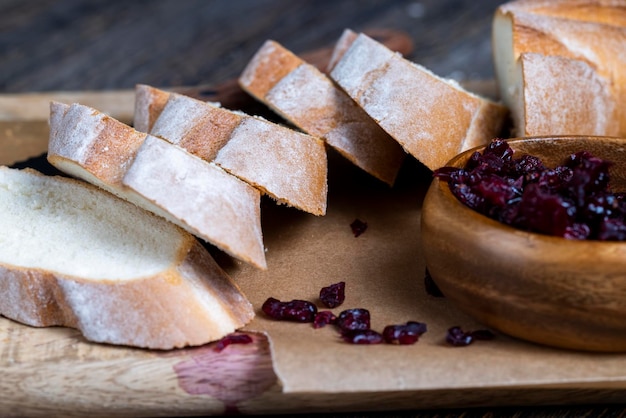 Cranberry and sliced soft fresh baguette on a cutting board and table