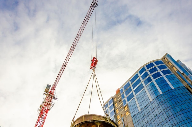 Crane boom with cargo on the sky background.