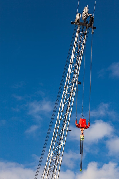 Crane boom with a stabilizer and a hook against a blue sky