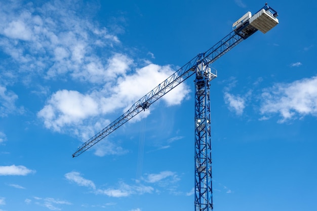 Crane and a building under construction against a blue sky background