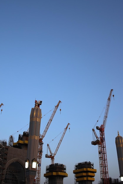 Crane and building under construction against blue sky