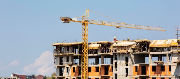 Crane on the construction of a brick house in summer