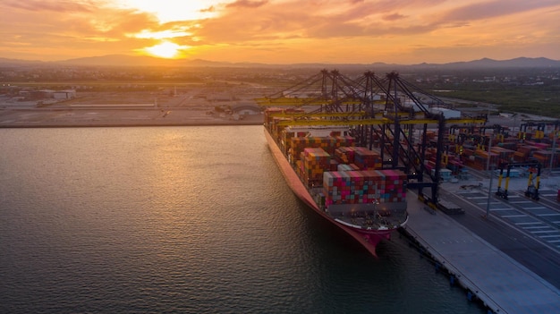 Crane loanding cargo container to container ship in the international terminal yard port concept freight shipping by ship at sunrise