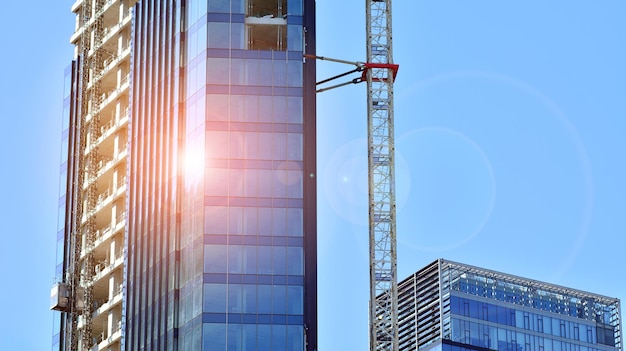 a crane stands in front of a building with the sun shining on it.