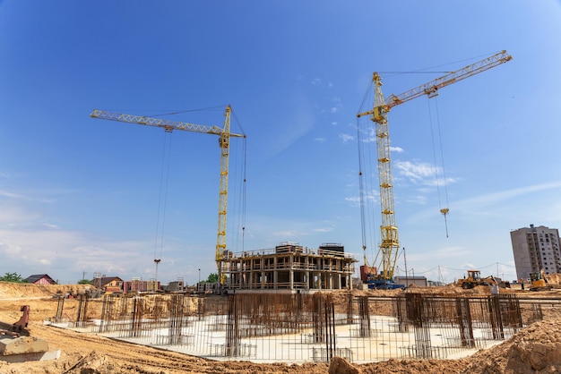 Cranes and building construction site against blue sky