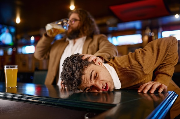 Crazy behavior of football fans at sport pub. Man pulling other guy face on bar counter desk and drinking beer