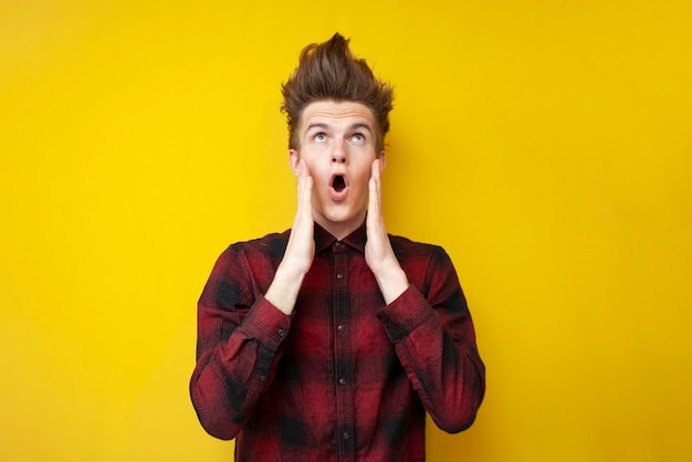 Crazy guy with a funny hairstyle is surprised on a yellow isolated background