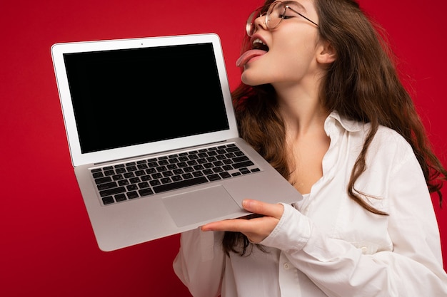 Crazy mad beautiful brunette curly young woman holding computer laptop wearing glasses white shirt