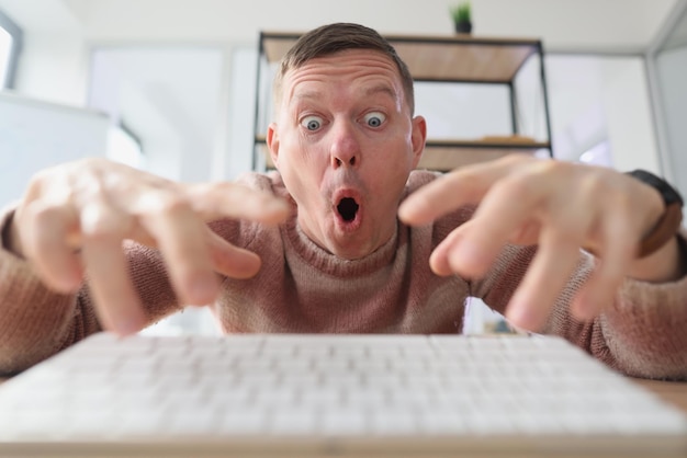 Crazy man with surprised facial expression types on keyboard