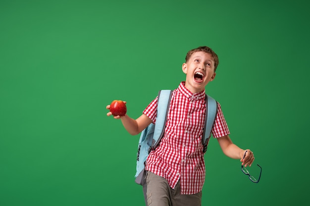 Crazy schoolboy holds glasses and apple in his hands