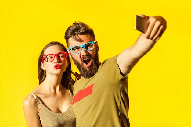 Crazy selfie beautiful friends macking selfie on yellow background